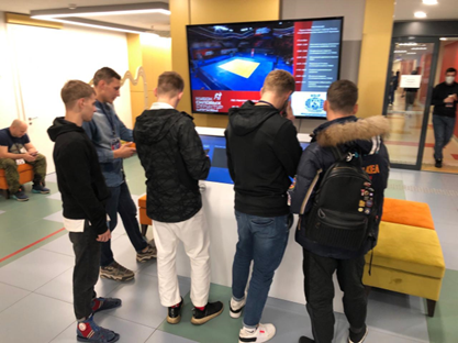Группа зрителей ознакамливаются с результатами, отображающиеся в Инфоцентре